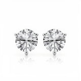 The image shows two stud earrings with large round-cut clear gemstones held by three-prong white metal settings. They are displayed side by side against a clean white background in a minimalist product photography style, unmounted on the ear. Bright, even lighting accentuates the facets of the stones and the polished finish of the metal while casting subtle reflections beneath each earring. The simple composition and stark backdrop bring full focus to the symmetrical arrangement and brilliance of the gems.