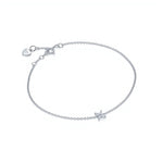 One delicate bracelet is shown, crafted from polished sterling silver with a slender cable chain and an adjustable spring-ring clasp accented by a tiny heart-shaped tag with brand name Adorn By You. A small starburst motif formed of marquise-cut clear crystals sits slightly off-center on the chain, each stone set in a minimal prong setting that catches the light. The piece is laid flat against a stark white background and illuminated by soft, diffuse studio lighting that creates an even, high-key aesthetic.