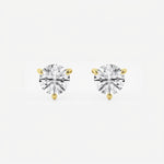 The image shows two stud earrings made from yellow gold. Each earring features a single round brilliant-cut diamond held in a three-prong setting that tapers elegantly toward the stone. Designed to be worn on the earlobes, the studs are shown unattached and arranged side by side on a seamless white surface. Crisp, even studio lighting creates a high-key look with soft shadows beneath the earrings, emphasizing their sparkle and symmetry.  | Adorn By You