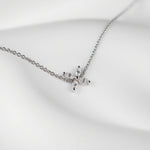 One delicate bracelet is shown, crafted from polished sterling silver with a slender cable chain and an adjustable spring-ring clasp accented by a tiny heart-shaped tag with brand name Adorn By You. A small starburst motif formed of marquise-cut clear crystals sits slightly off-center on the chain, each stone set in a minimal prong setting that catches the light. The piece is laid flat against a stark white background and illuminated by soft, diffuse studio lighting that creates an even, high-key aesthetic.