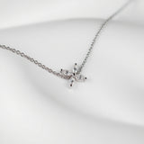 One delicate bracelet is shown, crafted from polished sterling silver with a slender cable chain and an adjustable spring-ring clasp accented by a tiny heart-shaped tag with brand name Adorn By You. A small starburst motif formed of marquise-cut clear crystals sits slightly off-center on the chain, each stone set in a minimal prong setting that catches the light. The piece is laid flat against a stark white background and illuminated by soft, diffuse studio lighting that creates an even, high-key aesthetic.