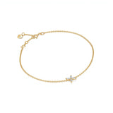 One bracelet of delicate yellow gold chain features a small four-petal star of white marquise-cut stones set in prongs at its center, with a spring-ring clasp and a tiny heart tag saying Adorn By You on the extender. The piece is laid flat against a seamless white background under soft, even lighting in a high-key, top-down composition. The polished gold tones and sparkling gemstones are sharply in focus, giving the image a crisp, professional product-shot style. | Adorn By You