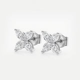 A pair of stud earrings crafted in white gold features two four-petaled floral motifs, each petal formed by a sparkling marquise-cut diamond set around a tiny polished gold bead. The cool silver tones of the metal perfectly complement the clear brilliance of the diamonds, creating a refined yet eye-catching silhouette. The earrings lie side by side on a seamless white background under bright, even studio lighting, highlighting their mirror-shiny finish and crisp faceted sparkle.