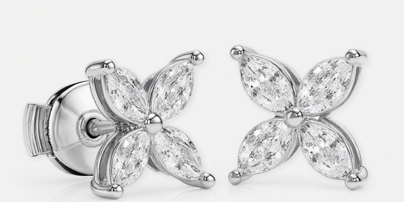 A pair of stud earrings in white gold features eight marquise-cut diamonds\u2014four per earring\u2014arranged symmetrically as a four-petal flower around a polished round center. Each diamond petal is secured by discreet prongs that emphasize the delicate floral motif. They sit side by side against a seamless white background under bright, even studio lighting that accentuates the metal\u2019s sheen and the stones\u2019 brilliance in a clean, high-key photographic style.